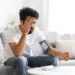 Man checking blood pressure at home while experiencing symptoms linked to sinusitis and hypertension