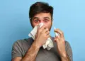 Man experiencing nasal congestion and shortness of breath while using nasal spray