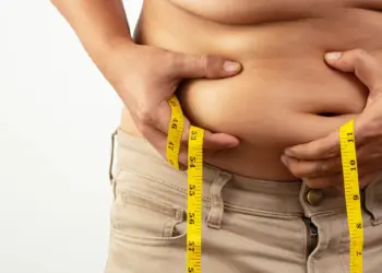 person holding and measuring excess abdominal skin and fat, often referred to as an apron belly