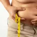 person holding and measuring excess abdominal skin and fat, often referred to as an apron belly