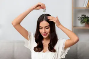 A woman applying Batana oil directly to her scalp using a dropper, highlighting the key benefits of Batana Oil for promoting hair growth, strengthening roots, improving scalp health, and reducing hair fall.