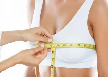 Vampire breast lift procedure showing a healthcare professional measuring a woman’s bust with a measuring tape for cosmetic enhancement.